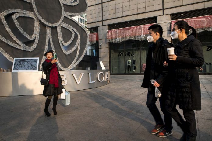 Pedestrians walk past a shopper taking a selfie; China's generation z;