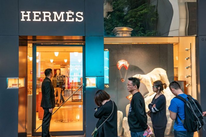 Shoppers wait in line outside a Hermes International store