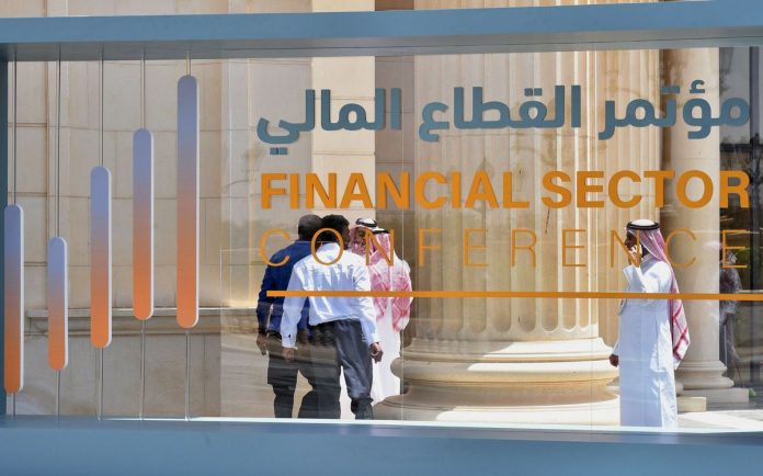 Saudi participants pass by a sign of the Financial Sector Conference held in Riyadh, on April 24, 2019.